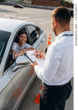 Using pen and writing results into notepad. Woman is trying to pass exam in the driving school Using pen and writing results into notepad. Woman is trying to pass exam in the driving school 137819877