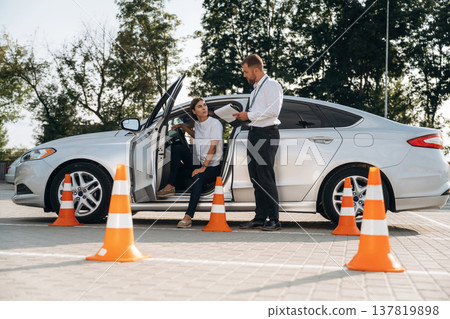 Using pen and writing results into notepad. Woman is trying to pass exam in the driving school Using pen and writing results into notepad. Woman is trying to pass exam in the driving school 137819898
