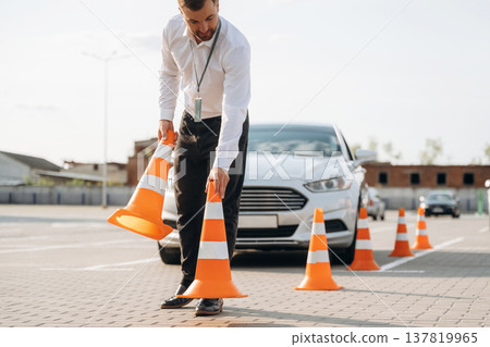 Driving school worker is outdoors near car Driving school worker is outdoors near car 137819965