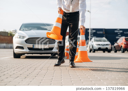 Driving school worker is outdoors near car Driving school worker is outdoors near car 137819966