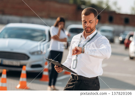 Working with information, holding notepad, woman is sad. Man instructor in the driving school Working with information, holding notepad, woman is sad. Man instructor in the driving school 137820106