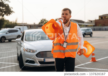 Wellness conception, having fun with the cones. The road worker in orange uniform is with cones near car 137820167