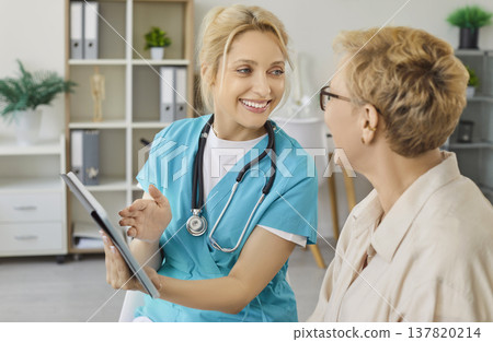 Nurse using tablet to show good health news to older woman on consultation Nurse using tablet to show good health news to older woman on consultation 137820214