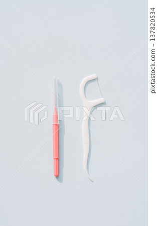 Interdental brush next to a dental floss pick, minimal comparison of interdental cleaning tools Interdental brush next to a dental floss pick, minimal comparison of interdental cleaning tools 137820534