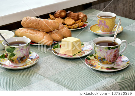 There are cups of tea and a plate of bread on the table. There are cups of tea and a plate of bread on the table. 137820559