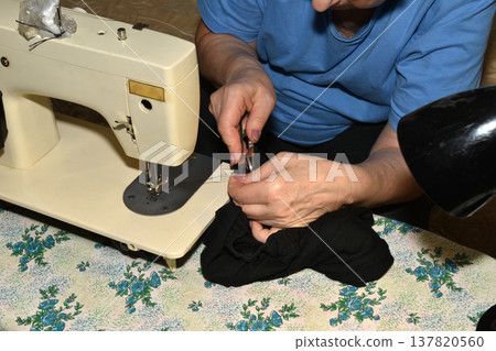 The seamstress works at the sewing machine. The seamstress works at the sewing machine. 137820560