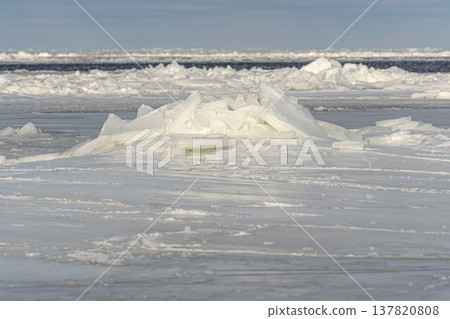 Ice formations float on water in a cold winter landscape near a frozen shore 137820808