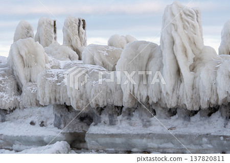 Winter weather creates icy formations on a shoreline near a lake at dawn 137820811