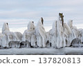Wooden posts stand partially buried in snow with ice formations during a cold winter day. 137820813