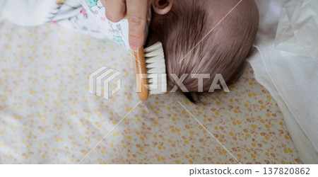 Mother brushing newborn baby soft hair with wooden brush 137820862