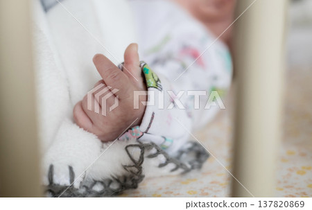 Close up of infant hand in baby crib Close up of infant hand in baby crib 137820869
