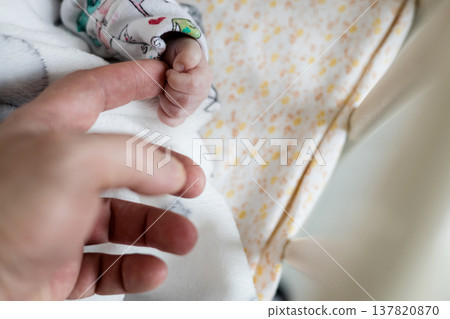 baby's tiny hand holding father's finger 137820870