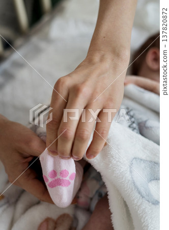 : Parent dressing newborn infant in cozy cotton socks 137820872