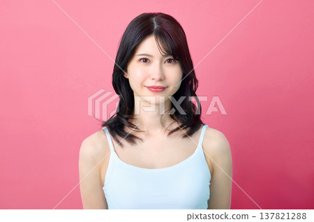 一位美麗的日本女性在粉紅色背景下微笑的肖像照。美容/護膚素材。 137821288