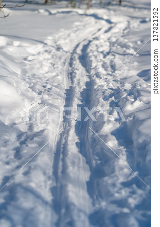 Pristine snow with footprints. Serene winter landscape with fresh ski marks. Tranquil snowcovered area featuring new footprints and brilliant sunlight casting shadows Pristine snow with footprints. Serene winter landscape with fresh ski marks. Tranquil snowcovered area featuring new footprints and brilliant sunlight casting shadows 137821592