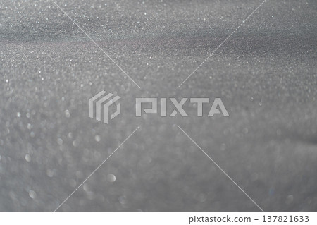 Frozen snow with shimmering light effects. Sunlit snow surface featuring bokeh effects and sparkling crystal reflections suitable for photography or product displays 137821633