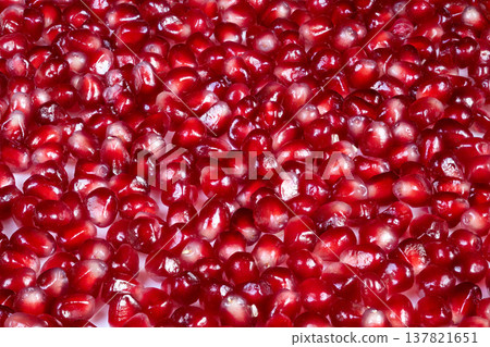 Glistening arils for culinary use. Vibrant garnish suggestion with bright pomegranate seeds. Detailed view of glossy pomegranate arils perfect for gourmet presentation 137821651