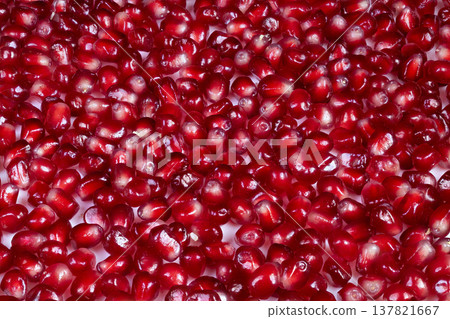 Red seeds with dewy shimmer. Translucent arils forming colorful health image. Closeup of crimson pomegranate arils creating lively mosaic symbolizing vitality and wellness Red seeds with dewy shimmer. Translucent arils forming colorful health image. Closeup of crimson pomegranate arils creating lively mosaic symbolizing vitality and wellness 137821667