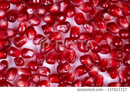 Vivid berry details. Highcontrast image displaying shining red seeds with droplets. Intimate view of polished pomegranate seeds adorned with sparkling juice beads and pattern 137821727