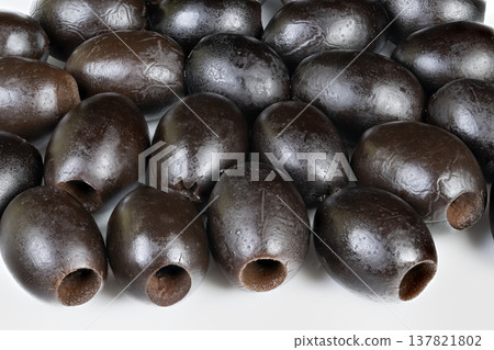 Pitted black olives lined for packaging, commercial food supply context with cured and salted impression, marketready presentation on white surface, orderly arrangement 137821802