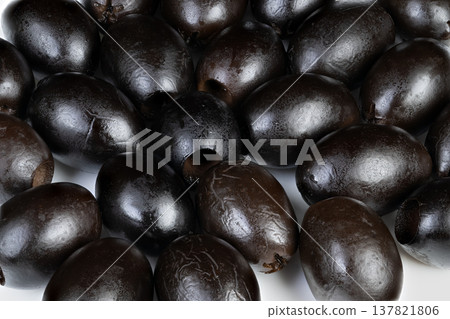 An artistic presentation featuring shiny black olives in detailed view. Detailed closeup of decorative black olives emphasizing their glossy finish and aesthetic appeal 137821806