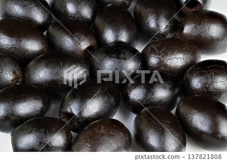 Black olives closeup. Highdetail macro shot of glossy black olives textured surface. Photographic closeup capturing luminous black olives with reflective oil surface details Black olives closeup. Highdetail macro shot of glossy black olives textured surface. Photographic closeup capturing luminous black olives with reflective oil surface details 137821808