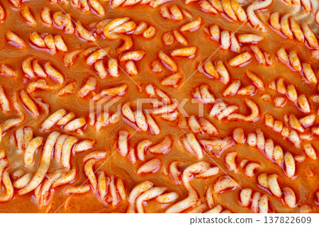 Steaming bowl of spicy instant ramen, curled noodles rising through aromatic broth, wisps of steam and seasoning granules, evokes latenight student meal or home kitchen comfort 137822609