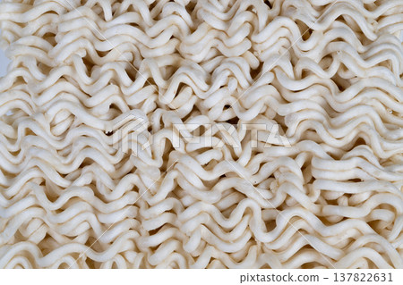 Compact wave pattern in instant noodles. Homey pantry staple with quick and easy meal appeal. Detailed view highlighting textured surface of instant dry noodle grains Compact wave pattern in instant noodles. Homey pantry staple with quick and easy meal appeal. Detailed view highlighting textured surface of instant dry noodle grains 137822631