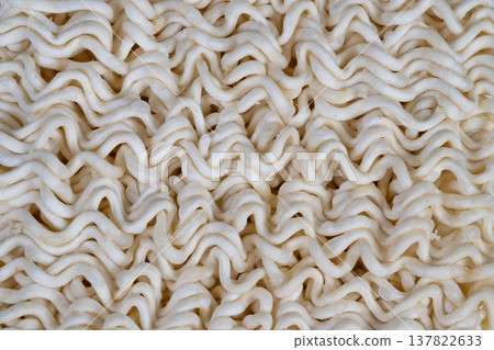 Macro dry instant noodles texture showcasing tight wavy strands and fine flour dust, neutral beige tones, soft diffuse lighting highlighting repetitive pattern and tactile surface 137822633