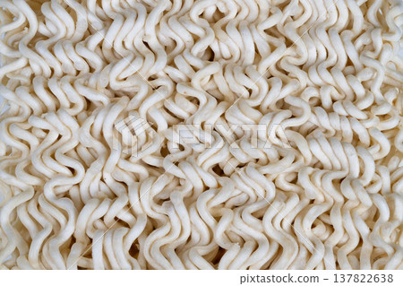 Closeup of crispy noodles surface. Detailed view of ridged dry noodles texture. High magnification revealing porous surface and tactile ridges of instant noodles Closeup of crispy noodles surface. Detailed view of ridged dry noodles texture. High magnification revealing porous surface and tactile ridges of instant noodles 137822638
