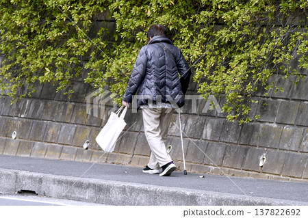 一張日本橫濱的城市景觀照片……一位拄著拐杖（戴著口罩）的老婦人低著頭走在人行道上……人生究竟是什麼……？ = 橫濱市 137822692