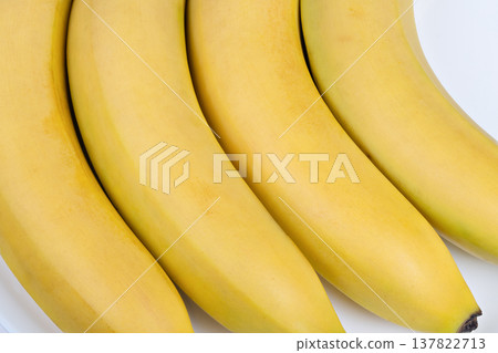 Closeup of fresh organic bananas. Ripe bananas with curving shapes and green tips. Vivid display of seasonal tropical bananas showcasing natural ripeness and vibrant colors Closeup of fresh organic bananas. Ripe bananas with curving shapes and green tips. Vivid display of seasonal tropical bananas showcasing natural ripeness and vibrant colors 137822713