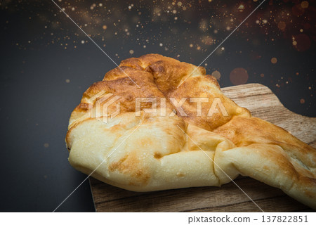 The naan, baked in a special oven and placed on a wooden board, has a delicious-looking color. The naan, baked in a special oven and placed on a wooden board, has a delicious-looking color. 137822851