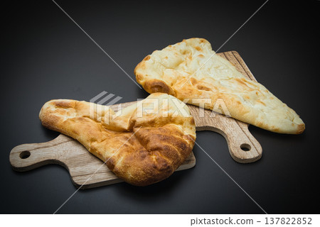 The naan, baked in a special oven and placed on a wooden board, has a delicious-looking color. The naan, baked in a special oven and placed on a wooden board, has a delicious-looking color. 137822852
