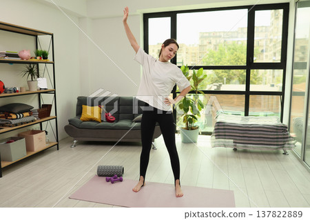 Stretching and relaxing in a cozy living room on a sunny day, embracing wellness and mindfulness in a tranquil home environment Stretching and relaxing in a cozy living room on a sunny day, embracing wellness and mindfulness in a tranquil home environment 137822889