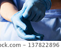 Healthcare professional putting on blue medical gloves 137822896