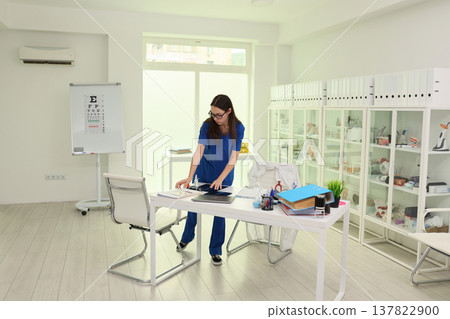 Medical professional organizes patient files in bright, modern clinic during busy daytime hours in urban setting 137822900