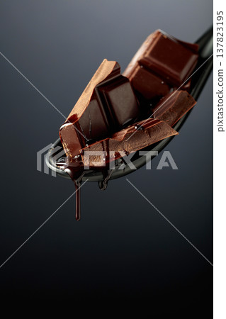 Melting pieces of bitter chocolate on a black background. Melting pieces of bitter chocolate on a black background. 137823195