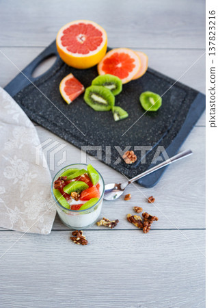 fresh yogurt dessert with fruits and nuts on wooden table 137823216