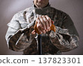 Soldier in camouflage uniform holding a cane, symbolizing veteran support and resilience 137823301
