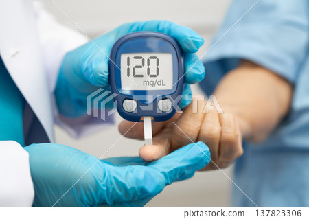 Asian doctor using digital glucose meter for check sample blood sugar level to treatment diabetes. Asian doctor using digital glucose meter for check sample blood sugar level to treatment diabetes. 137823306