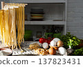 Homemade noodles hanging on wooden dryer rack over messy kitchen table background low angle front view 137823431