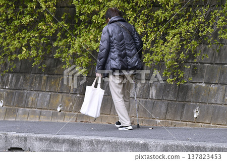 A picture of the cityscape of Yokohama, Japan...an elderly woman with a cane (wearing a mask) walking on the sidewalk with her head down...what is life...? = Yokohama city A picture of the cityscape of Yokohama, Japan...an elderly woman with a cane (wearing a mask) walking on the sidewalk with her head down...what is life...? = Yokohama city 137823453