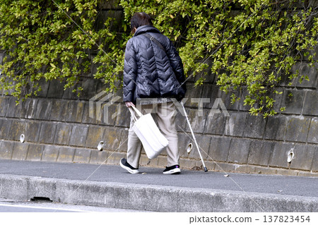A picture of the cityscape of Yokohama, Japan...an elderly woman with a cane (wearing a mask) walking on the sidewalk with her head down...what is life...? = Yokohama city A picture of the cityscape of Yokohama, Japan...an elderly woman with a cane (wearing a mask) walking on the sidewalk with her head down...what is life...? = Yokohama city 137823454
