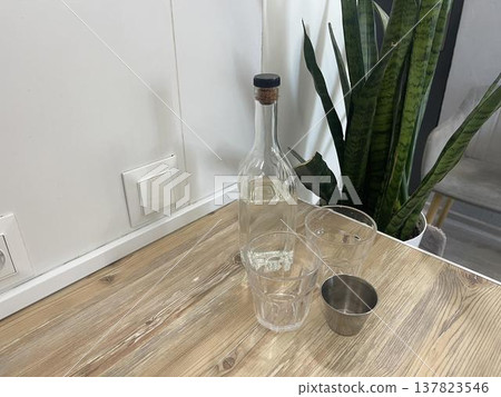 measuring cup and bottle of vodka on the table 137823546