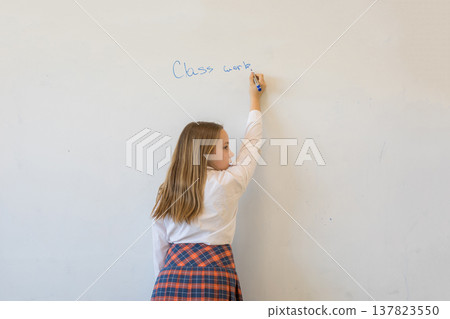 Beautiful young child girl in school uniform writing something o Beautiful young child girl in school uniform writing something o 137823550