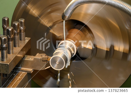 Precision finish cut operation on a metal shaft using a lathe machine with high-pressure liquid coolant for superior surface quality. 137823665