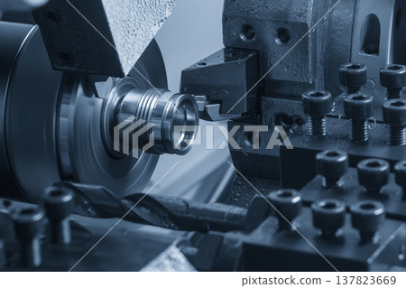Close-up of a high-precision Swiss-type multi-tasking CNC lathe performing a thread cutting process on small metal components. 137823669