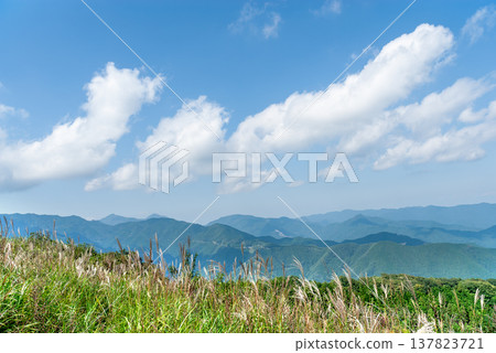 The spectacular view from the summit of Mt. Bōnoori (Bōnomine): white clouds floating in the autumn blue sky and the mountain ranges of Chichibu and Okutama. The spectacular view from the summit of Mt. Bōnoori (Bōnomine): white clouds floating in the autumn blue sky and the mountain ranges of Chichibu and Okutama. 137823721