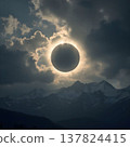 Solar Eclipse Framed by Dramatic Clouds Over Mountains 137824415